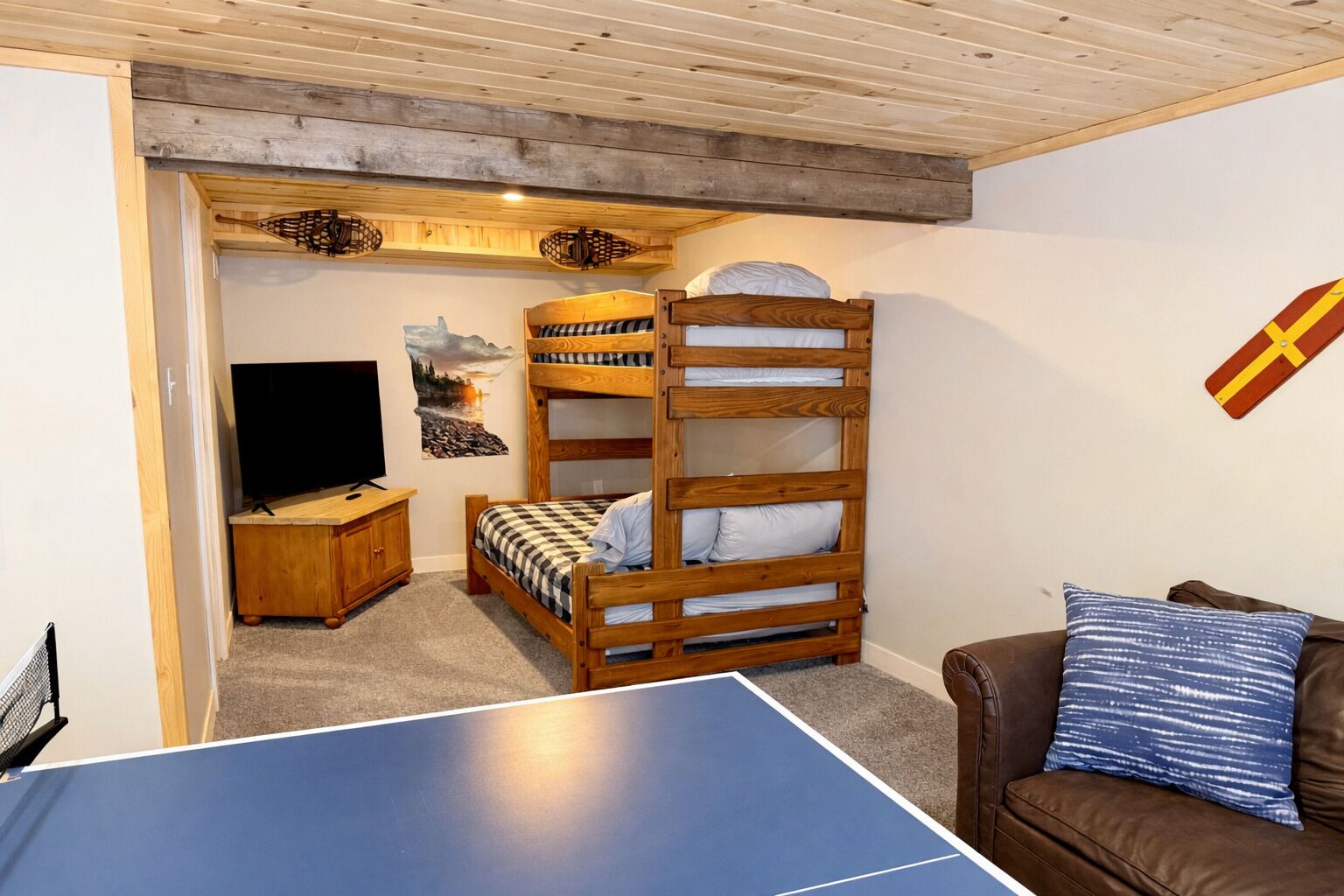 Una habitación con una cama litera, un escritorio con ordenador, una televisión y una mesa de ping pong.