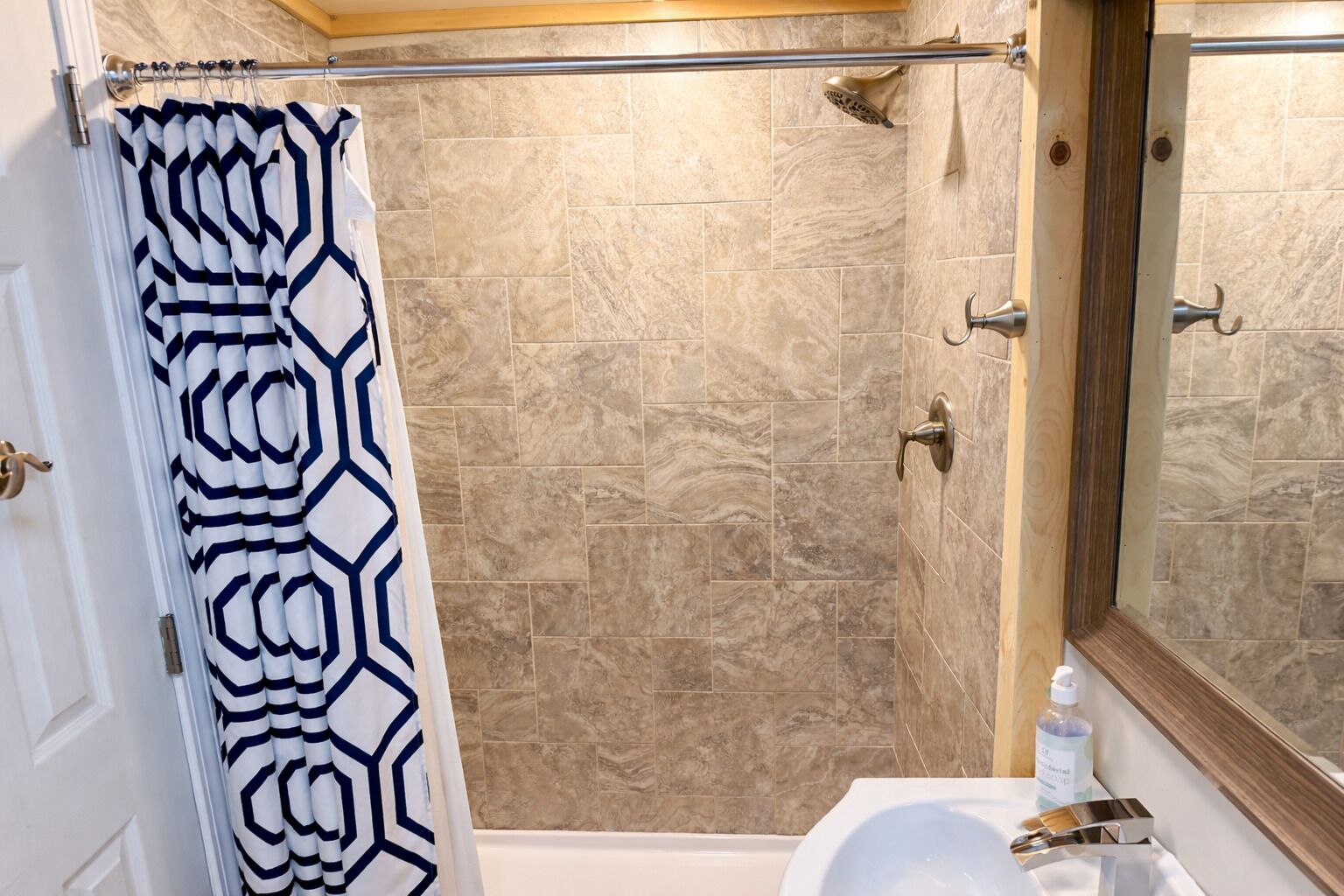Une salle de bain avec une douche, un lavabo et un miroir.