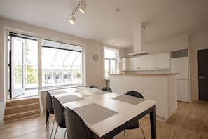 A modern kitchen with white cabinets, a central island, and a dining area with a table and chairs.