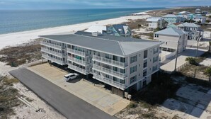 A beachfront hotel with multiple balconies, a parking area, and a view of the ocean. - Gulf Front, NW Top Floor Condo on Side Street in MXB ~ Surfside 17 (Mexico Beach)