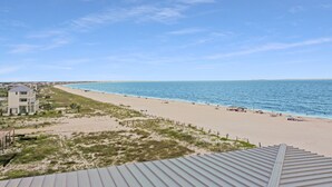 A beach view with a building, sandy beach, and ocean. - Gulf Front, NW Top Floor Condo on Side Street in MXB ~ Surfside 17 (Mexico Beach)