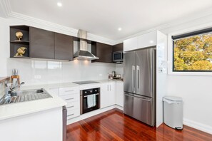 Una cocina moderna con armarios blancos, electrodomésticos de acero inoxidable y piso de madera.