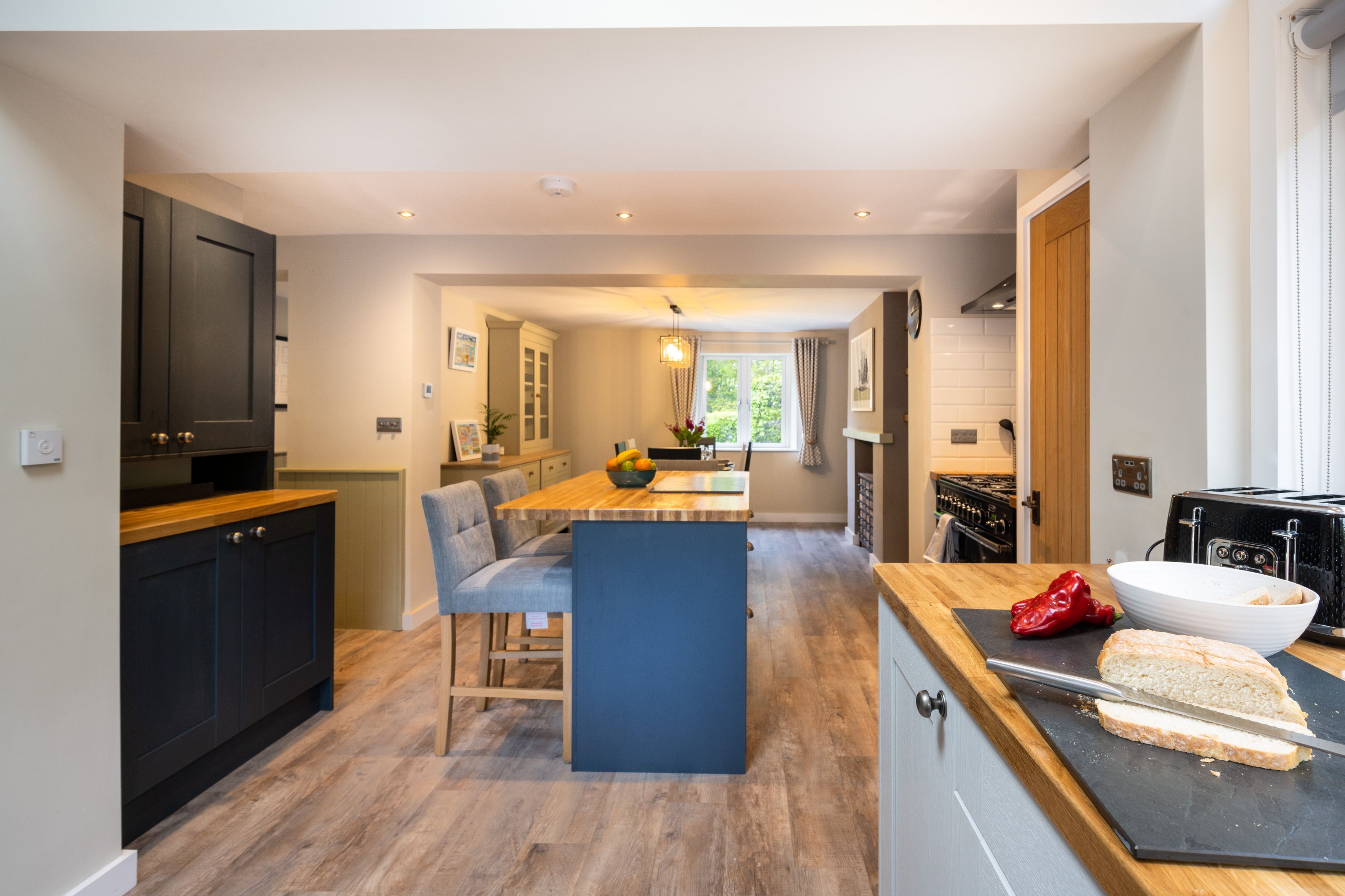 A modern kitchen with wooden flooring, a central island, and a dining area.