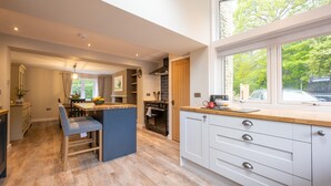 A modern kitchen with a central island, wooden flooring, and a large window offering a view of the outdoors.