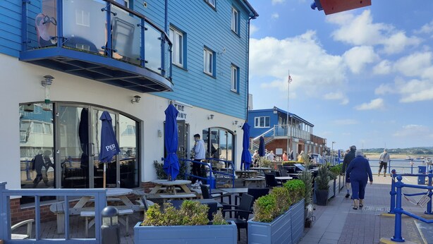 A seaside restaurant with outdoor seating, a view of the sea, and a blue building facade. - As close to the beach as you can possibly get !!!  uninterrupted estuary views (Exmouth)