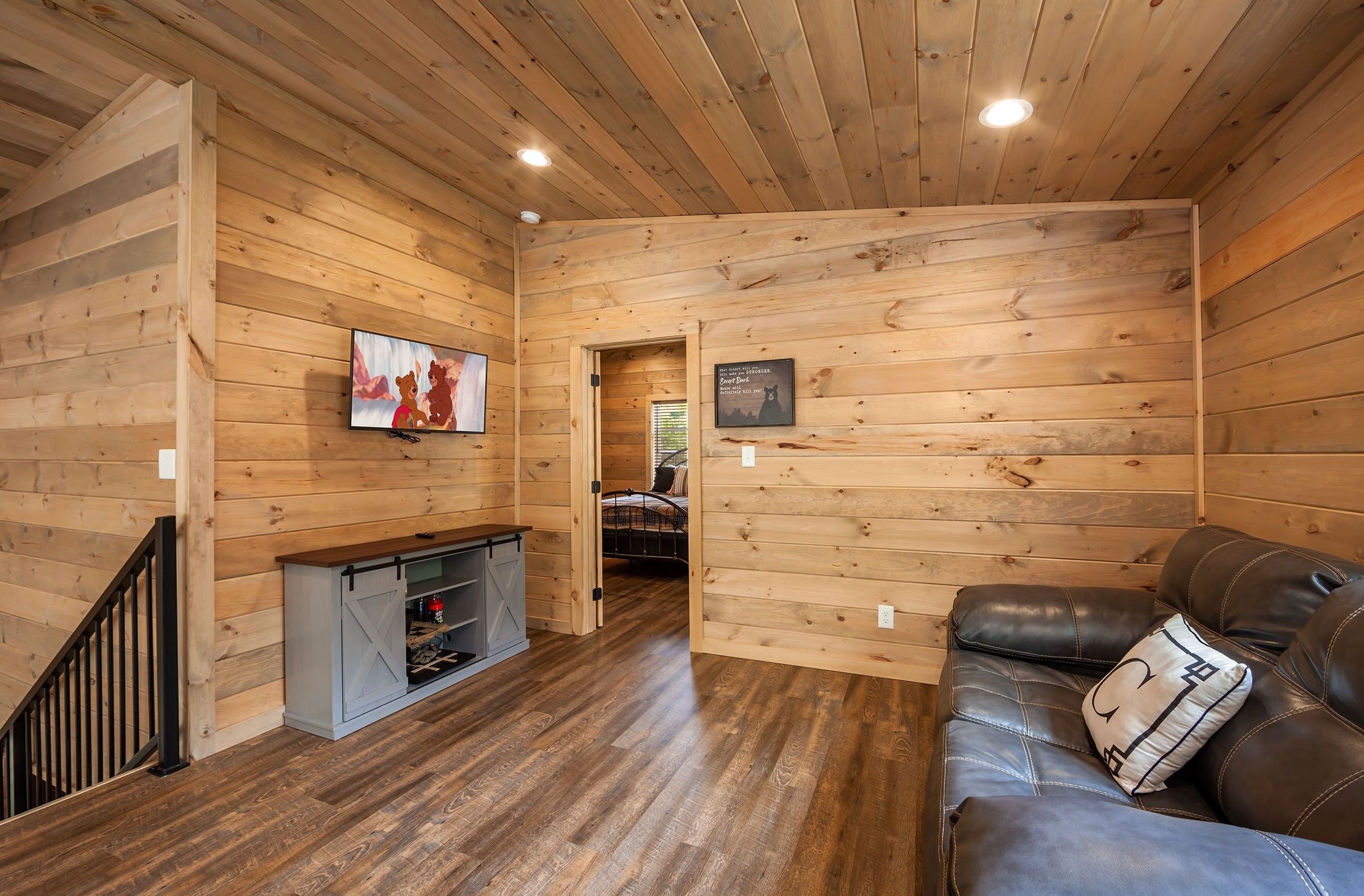 A wooden-paneled room with a fireplace, a leather sofa, and a television.