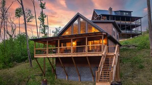 A modern house with a large deck and a staircase leading to a second level.