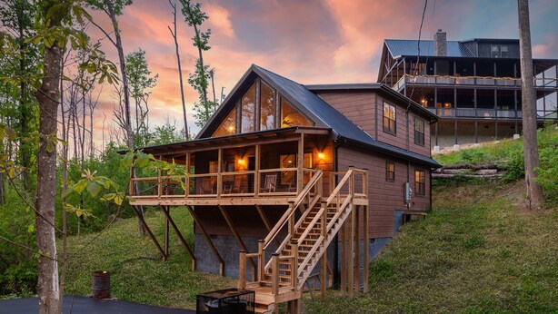 A wooden cabin with a balcony and a staircase leading to the upper level.
