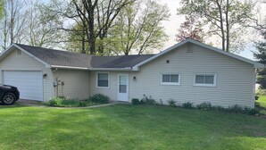 A single-story house with a garage, a front door, and a small porch area. - Lake Front home near Sister Lakes area.  Pontoon rental available. (Decatur)