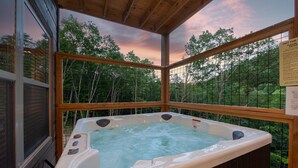 A hot tub in a wooden deck with a view of trees and a sunset. - Brand New Freedom Cabin with Large Deck by RedAwning (Sevierville)
