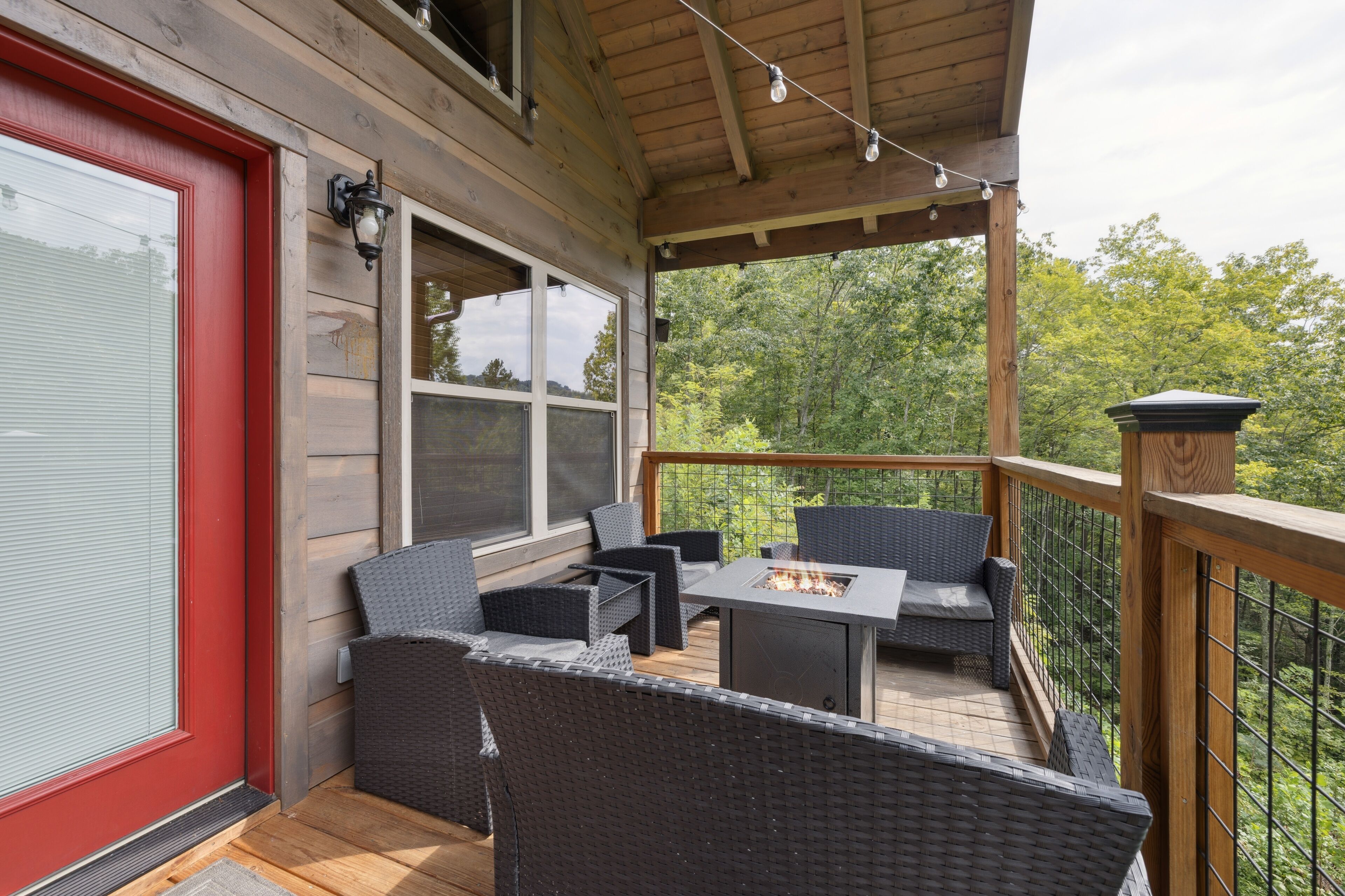 A covered outdoor patio with wicker furniture and a fire pit.