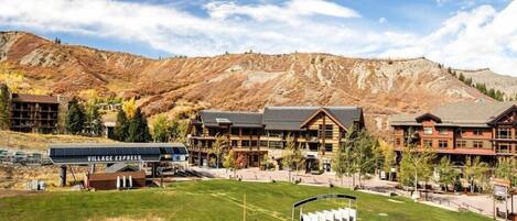 A lodge with a ski lift, surrounded by mountains and a clear sky.
