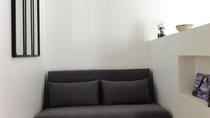 A modern living room with a dark grey sofa, two small round tables, a glass terrarium, and a framed picture on the wall. - L'etoile Loire - Un Jardin en Ville ! (Saumur)