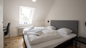 A modern bedroom with two beds, a desk, and a radiator. - City Town Square (Grasten)