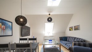 A modern living room with a sofa, chairs, a coffee table, and artwork on the walls. - City Town Square (Grasten)