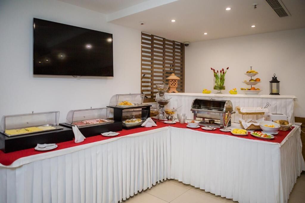 A buffet setup with various food stations, a television mounted on the wall, and a decorative lamp.