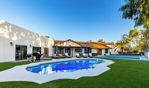 A modern house with a swimming pool, outdoor furniture, and a patio area.