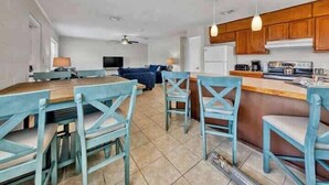 Amplia sala de estar con una mesa y sillas de comedor, una cocina con armarios de madera y un ventilador de techo.