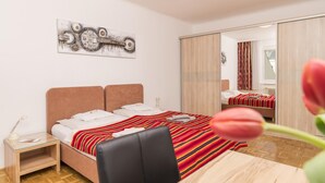 Un dormitorio moderno con cama, mesita de noche, escritorio y silla.