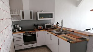 A compact kitchen with white cabinets, a built-in oven, a microwave, and a coffee maker. - Central Loft Apartment (Ueckermünde)