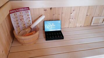 Ein Sauna-Bereich mit einer Holzbank, einem Holzeimer und einer Bürste sowie einer Produktbox.