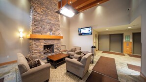 A living room with a stone fireplace, sofas, a coffee table, and a flat-screen TV mounted on the wall. - Fraser Crossing 3518 remodeled studio gas fireplace and views (Winter Park)