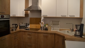 A modern kitchen with wooden cabinets, a built-in oven, a toaster, and a coffee maker. - Ferienwohnung mit Balkon im Zentrum von Eberwalde (Eberswalde)