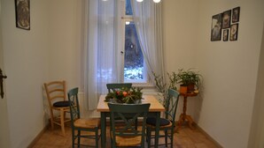 A dining area with a wooden table and chairs, a potted plant, and a window with curtains. - Ferienwohnung mit Balkon im Zentrum von Eberwalde (Eberswalde)