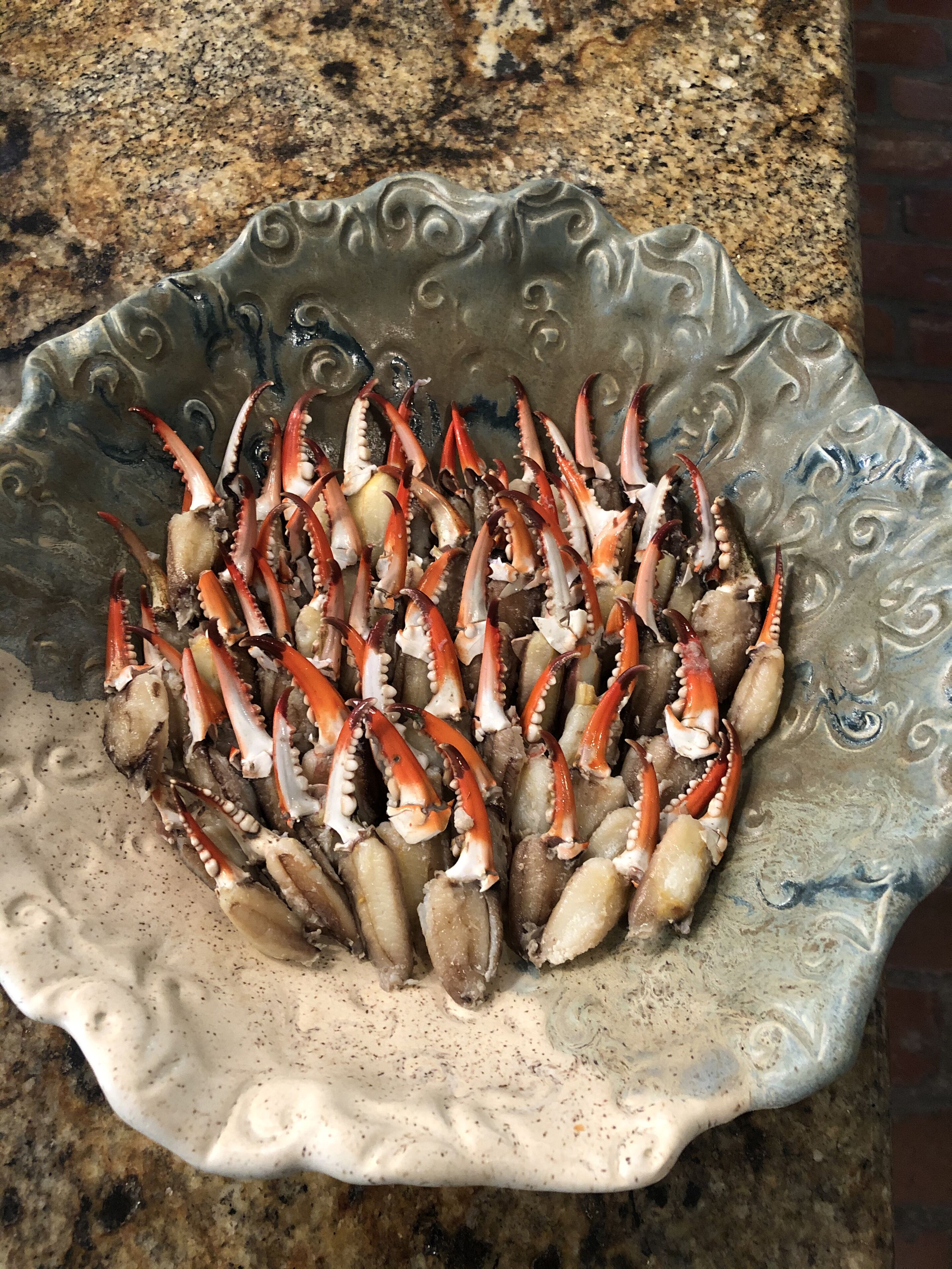 A decorative bowl filled with cooked crabs on a granite countertop.