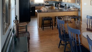 Una cocina amplia con armarios de madera, una isla central y un comedor con sillas azules.