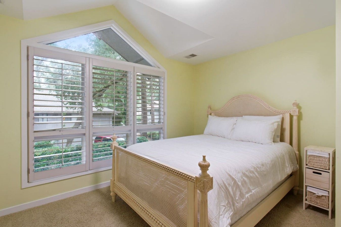 A bedroom with a bed, a window, and a nightstand.