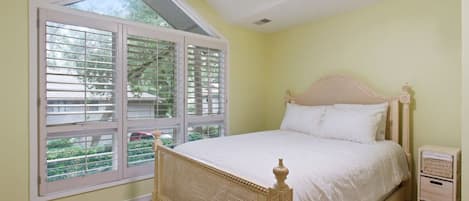 A bedroom with a bed, a window, and a nightstand.