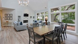A spacious dining area with a wooden table and chairs, a grey sofa, and a fireplace. - Direct Beach Path & Pool Near The Salty Dog Cafe (Hilton Head Island)