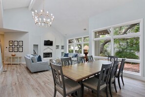 A spacious dining area with a wooden table and chairs, a grey sofa, and a fireplace.