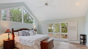 A bedroom with a large bed, two bedside tables with lamps, a dresser, a ceiling fan, and a large window with shutters. - Direct Beach Path & Pool Near The Salty Dog Cafe (Hilton Head Island)