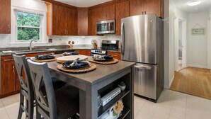 A modern kitchen with wooden cabinets, stainless steel appliances, and a dining area with a table set for four.