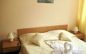 A hotel room with a bed, two bedside lamps, and a nightstand with a lamp.