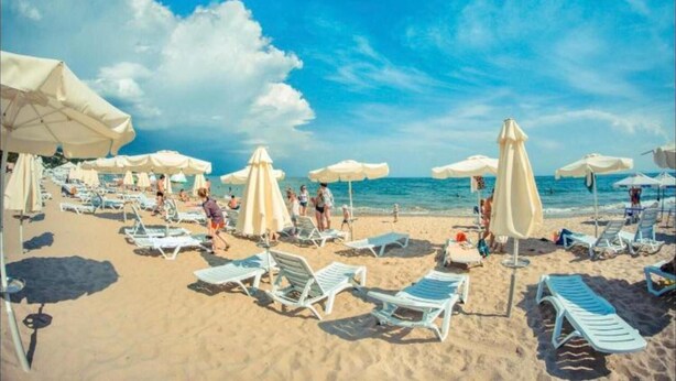 A beach with sun loungers and umbrellas, a clear sky, and the ocean in the background. - New & Stylish Sun Break Apartment in Sveti Vlas (Sveti Vlas)