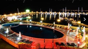 A nighttime view of a resort with a large pool, lounge chairs, and a marina with boats. - New & Stylish Sun Break Apartment in Sveti Vlas (Sveti Vlas)