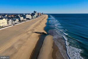 Ein Strand mit weitem Sandstreifen und einer Stadtkulisse im Hintergrund.