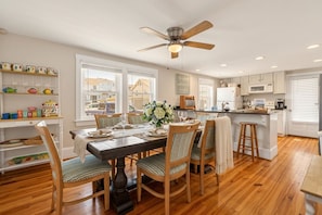 A dining area with a wooden table, chairs, and a ceiling fan.