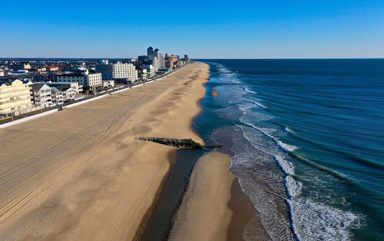 A beach with a long stretch of sand and a cityscape in the background.
