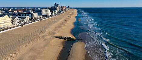 A beach with a long stretch of sand and a cityscape in the background.