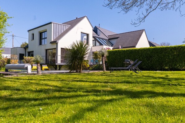 A modern two-story house with a well-maintained lawn and a hedge.