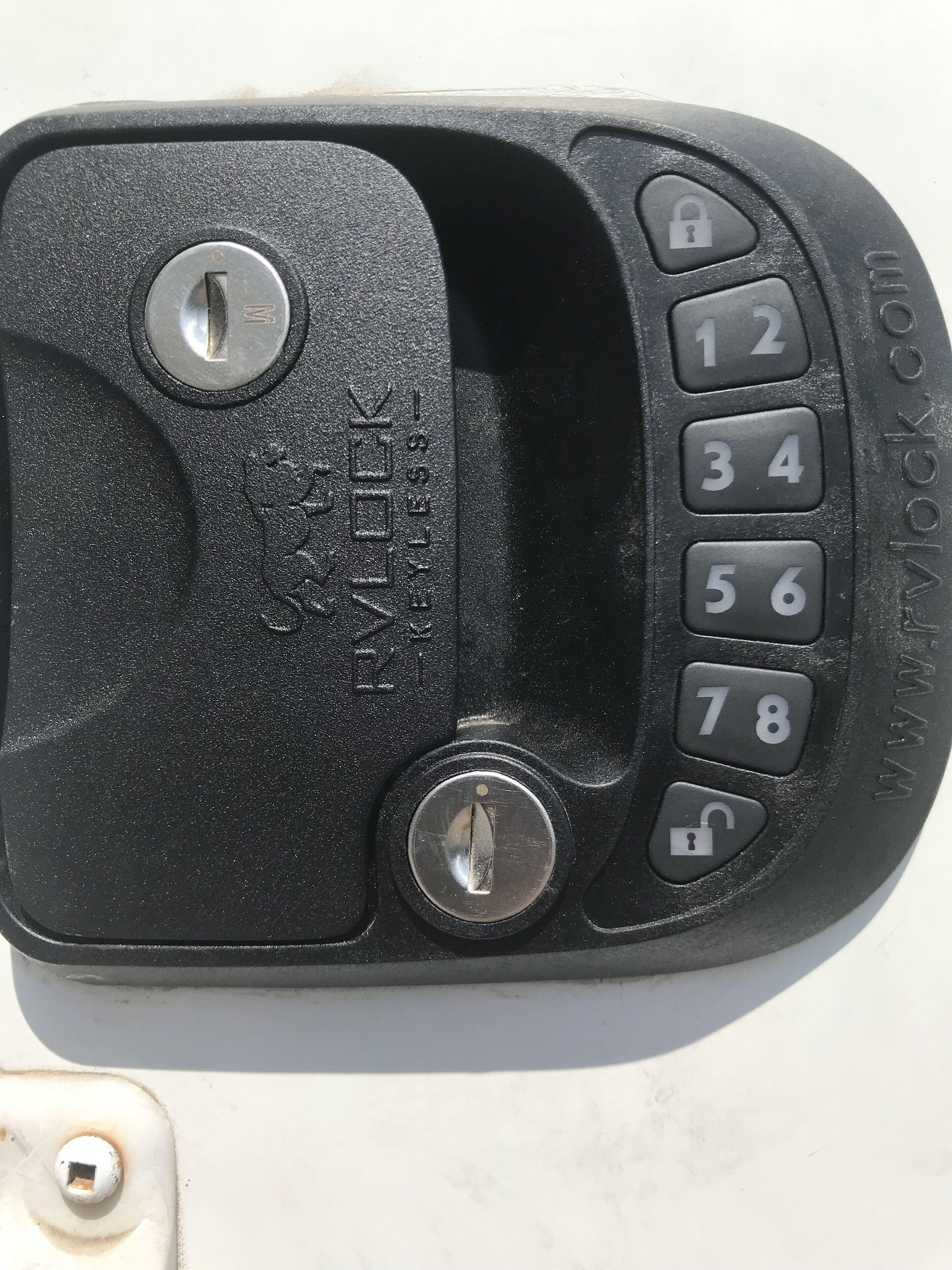 A black car key fob with a numeric keypad and a lock button.