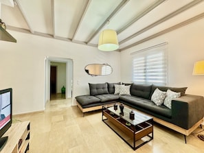 A modern living room with a sectional sofa, a glass coffee table, and a television on a wooden stand.