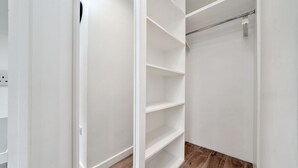 A walk-in closet with white walls and wooden flooring. - Cosy Apartment in the Heart of the City (London)