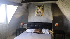 Un dormitorio con una cama grande, dos mesitas de noche, un cabecero y un tragaluz.