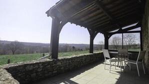 Una zona de estar al aire libre techada, con muros de piedra y vistas al campo.