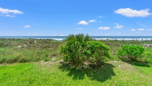 A coastal landscape with a clear sky, a beach in the background, and a small cluster of trees in the foreground. - Ocean Pier I 107-2BR/2BA Oceanfront Condo in Windy Hill (North Myrtle Beach)